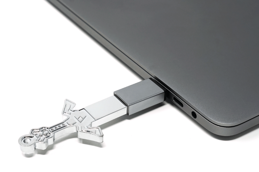 A silver USB drive plugged into a USB A to USB C adapter, which is then plugged into a silver computer