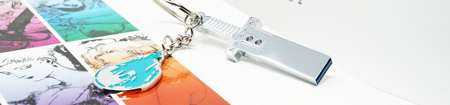 A silver USB next to a cyan keychain on top of books featuring art from Final Fantasy