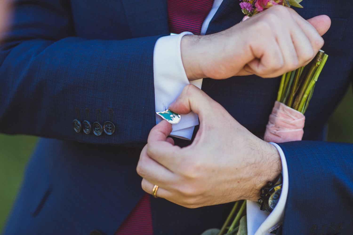 Cyan cufflinks being attached to a french cuff shirt