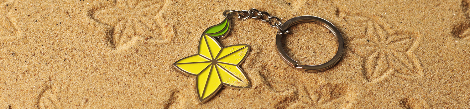 A yellow and green keychain on a sandy beach