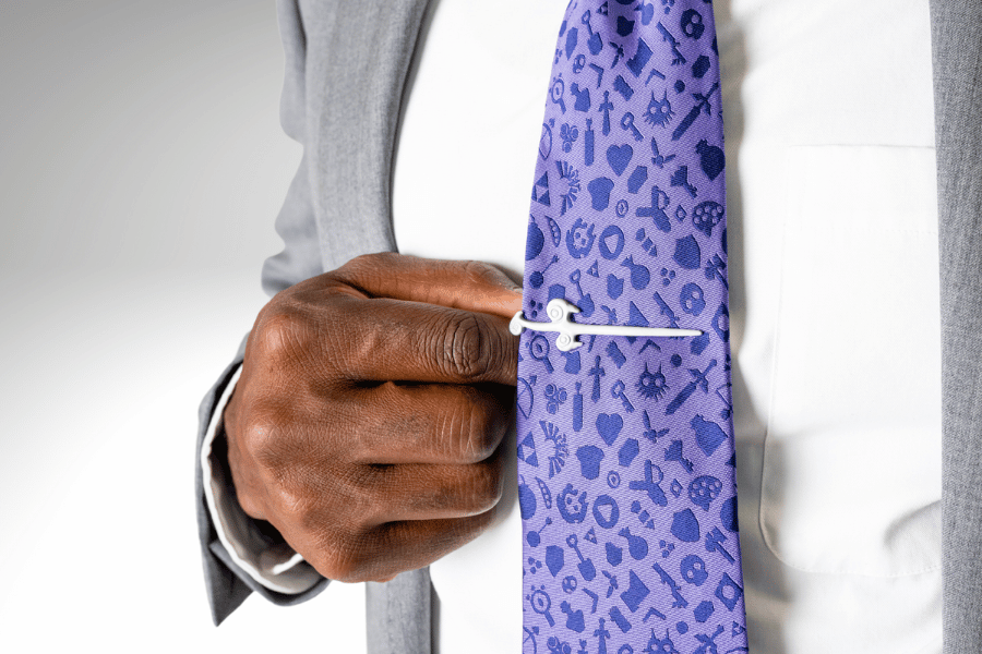 A white tie clip being clipped to a purple tie