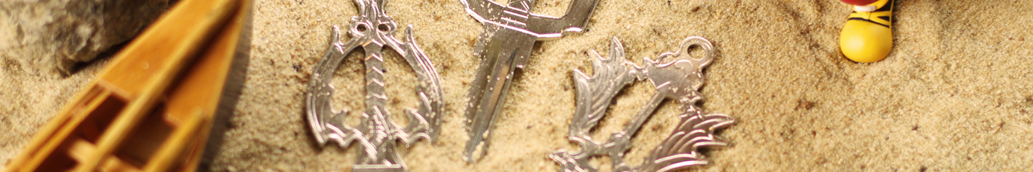 Three silver keys on a sandy beach, with a canoe on the left