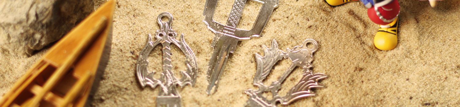 Three silver keys on a sandy beach