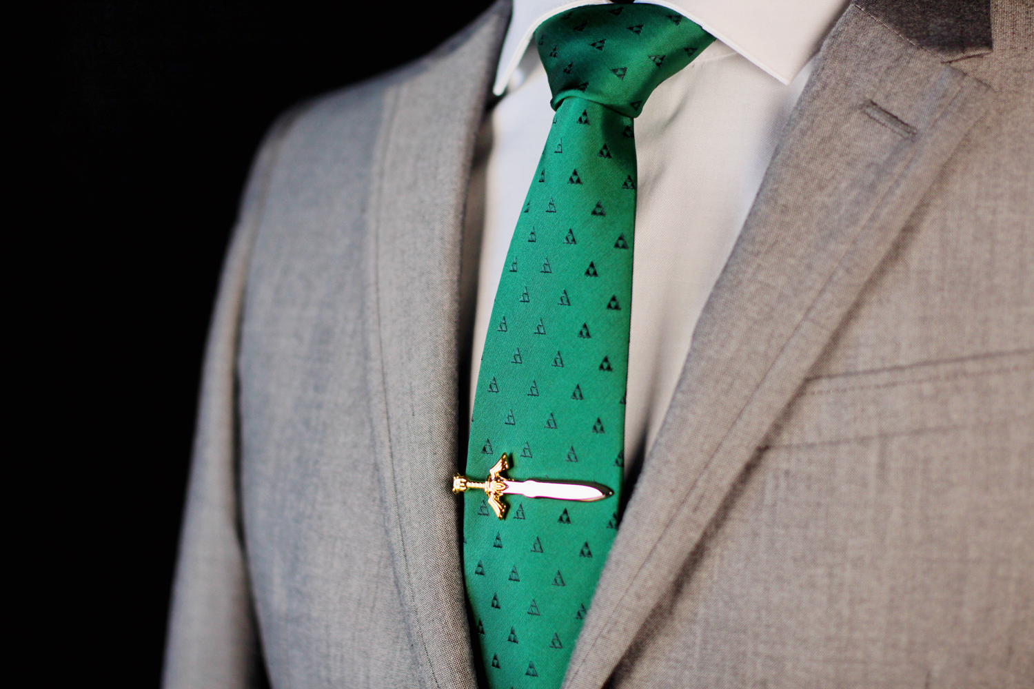 A silver and gold tie clip on a dark green tie