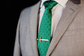 A silver and gold tie clip on a dark green tie