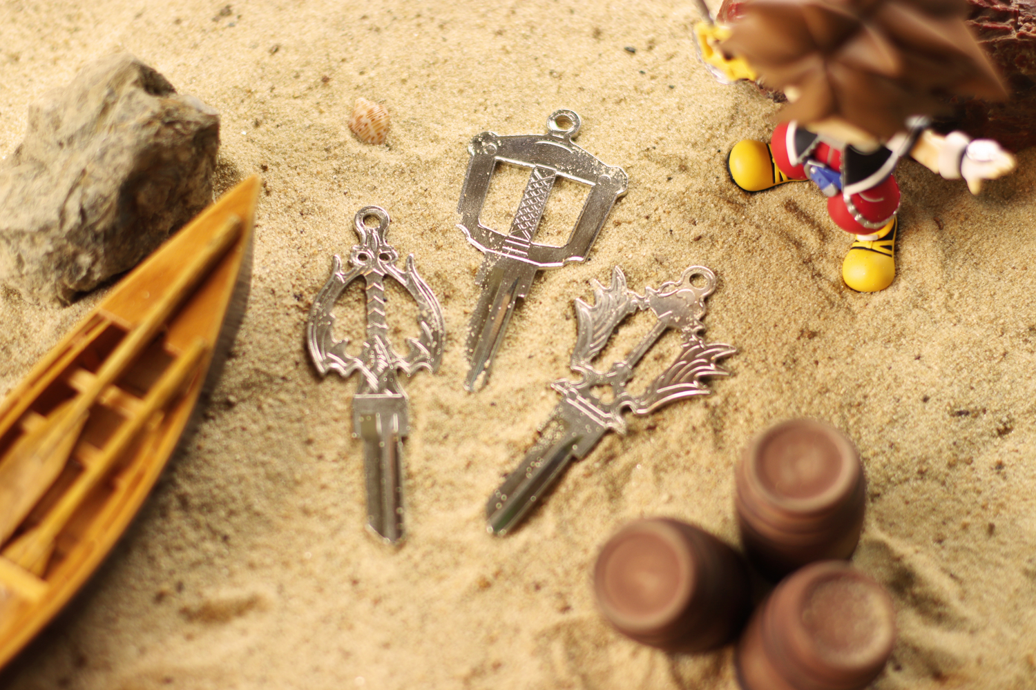 Three silver house keys on a sandy beach